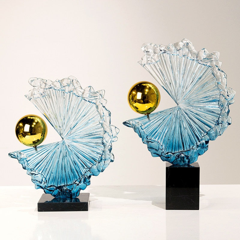 Front view of blue glass abstract wave sculpture with gold sphere on black base