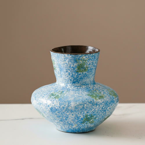 Blue and green speckled ceramic vase on white table