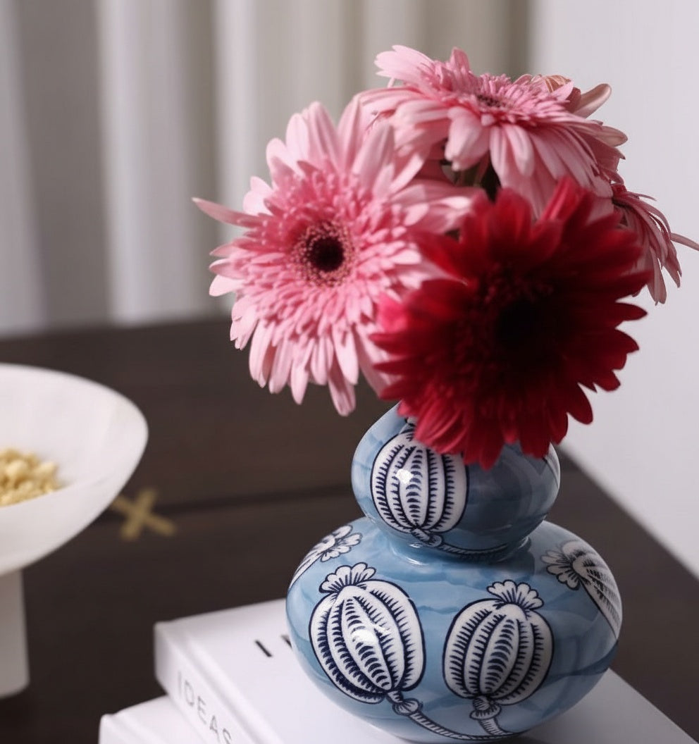 Side view of blue ceramic vase with pink flowers