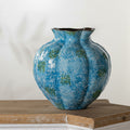Blue speckled ceramic fluted vase with wavy rim on wooden table