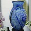 Front view of blue swirled art glass vase with red floral branch design