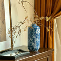 Blue and white ceramic vase with floral branch design on wooden console