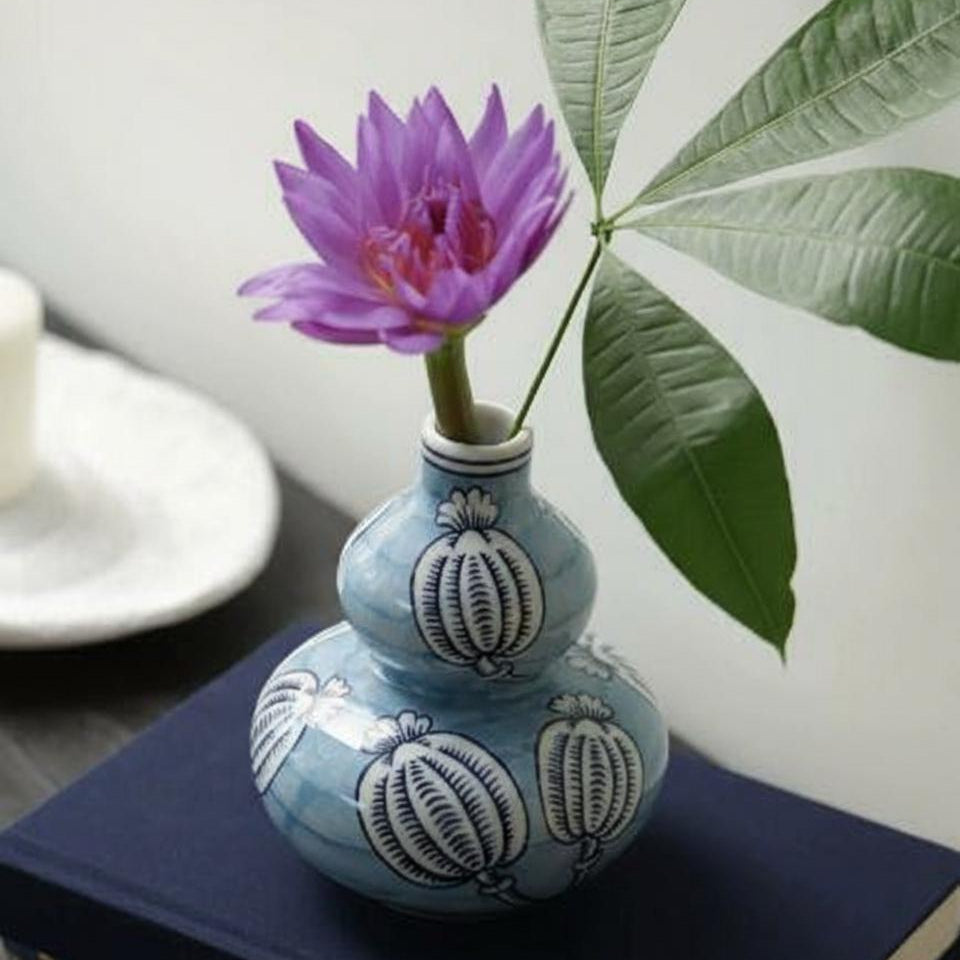 Blue and white ceramic double gourd vase with purple flower on blue book