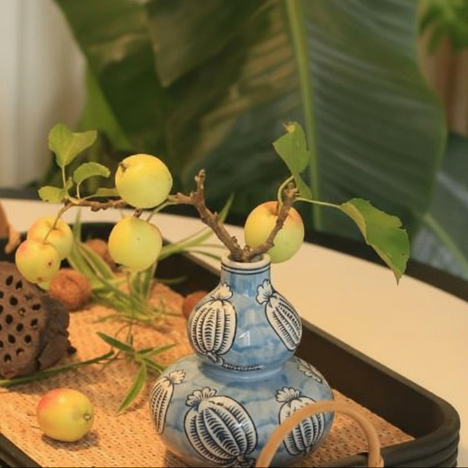 Ceramic bud vase with botanical pod pattern on rattan tray
