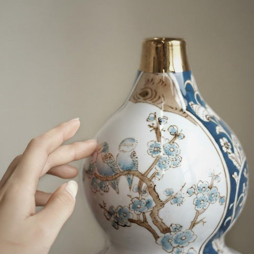 Close up of hand touching blue and white ceramic vase