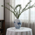 Hand-painted blue and white ceramic vase with fish motif and greenery