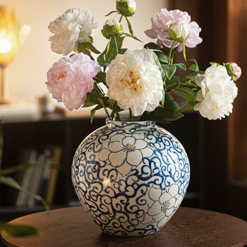 Blue and white floral ceramic spherical vase with gold accents on table