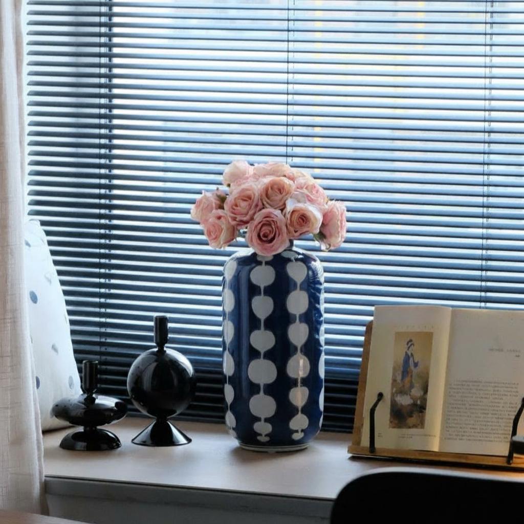 Blue and white patterned vase on window sill with roses
