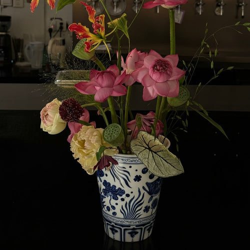 Porcelain vase styled with pink lotus flowers in a dark interior setting