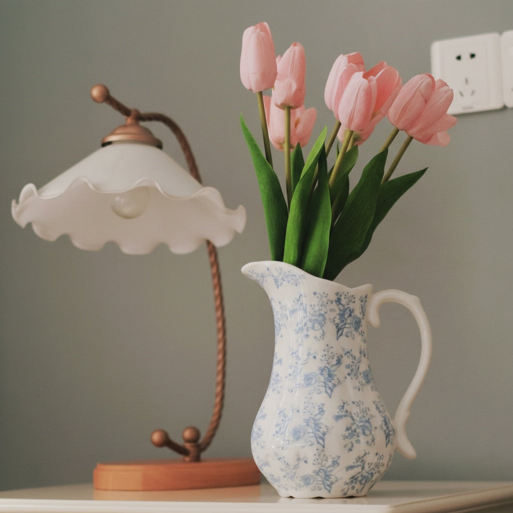 Ceramic floral pitcher vase on table next to lamp