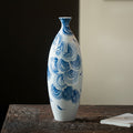 Tall slender blue and white porcelain vase with swirling wave art
