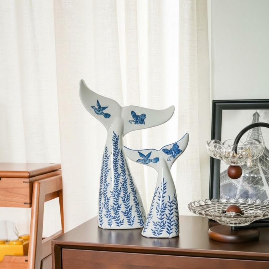 Large and medium porcelain whale tail sculptures on table