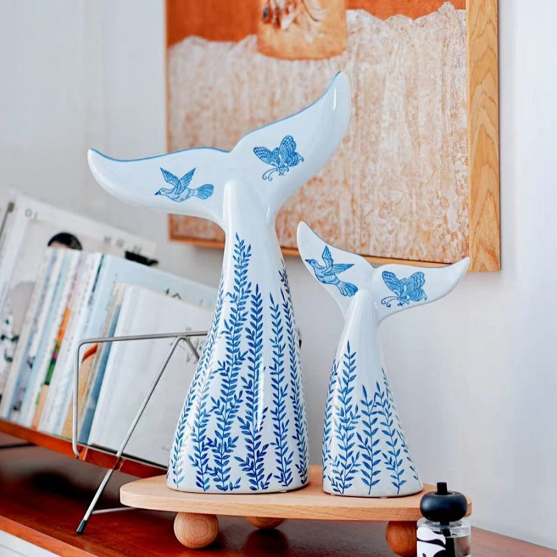 Porcelain whale sculptures styled on wooden shelf with books
