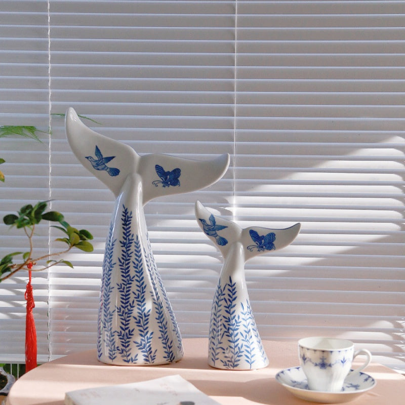 Whale tail sculptures in natural light near window blinds