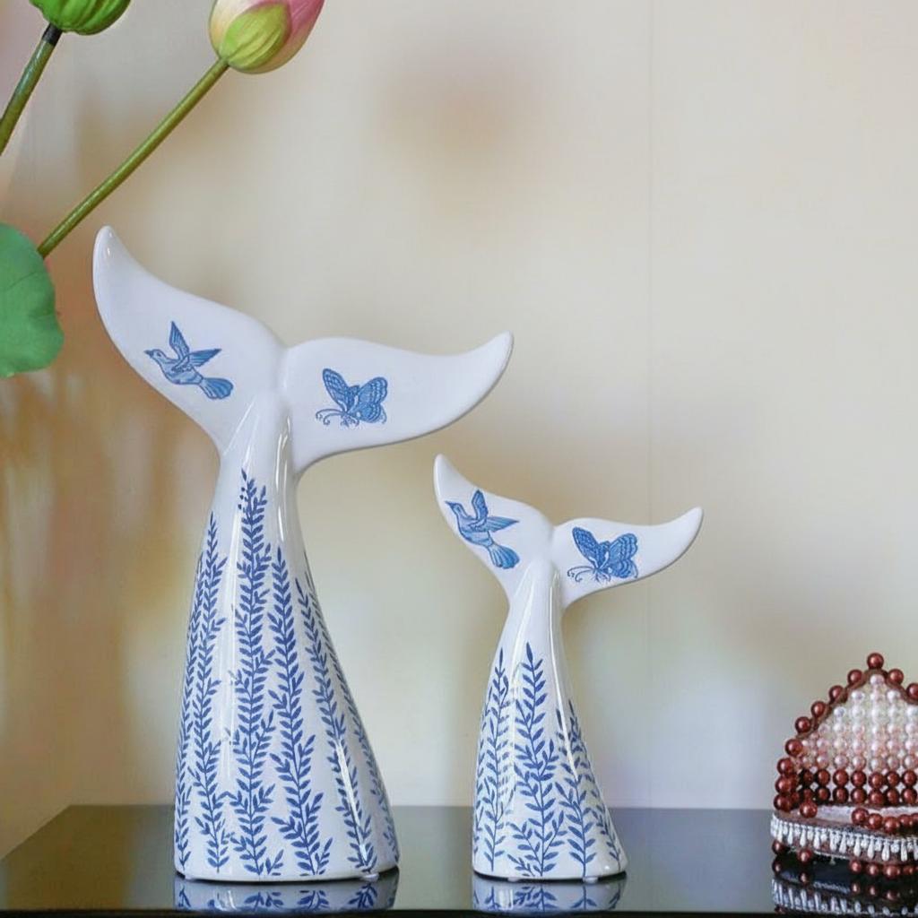 Pair of ceramic whale tails displayed with flowers