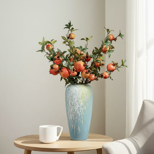 Blue ceramic vase with white splash pattern holding pomegranate branches