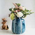 Blue and white striped ceramic vase with flowers on table