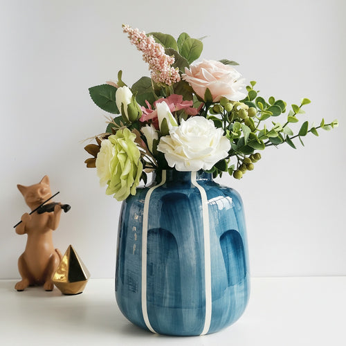 Blue and white striped ceramic vase with flowers on table
