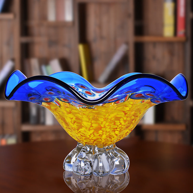 Empty blue and yellow crystal pedestal bowl on wood table