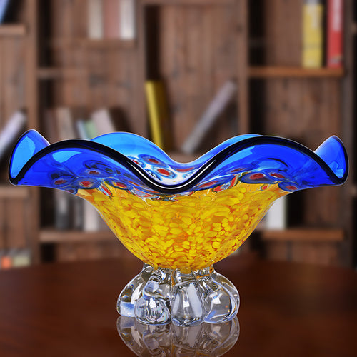 Empty blue and yellow crystal pedestal bowl on wood table