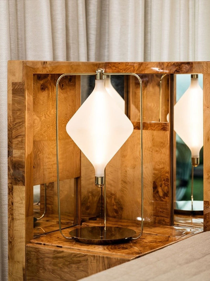 Detail of brass frame and diamond glass shade on wooden furniture
