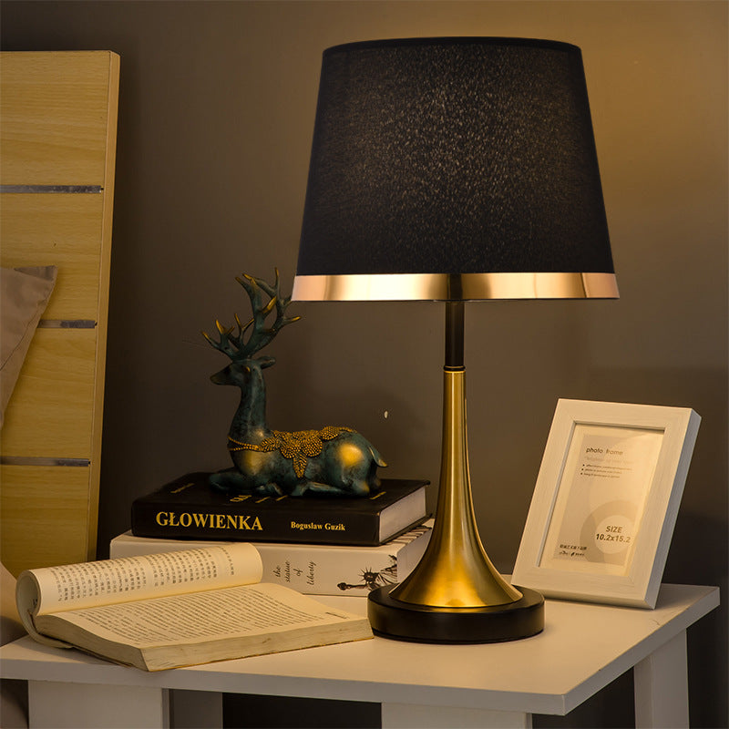 Brass and black tapered table lamp on bedside table