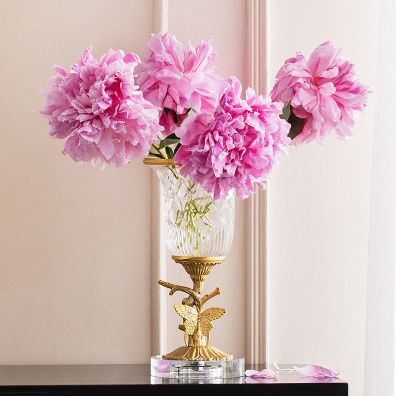 Brass and crystal butterfly vase holding pink flowers