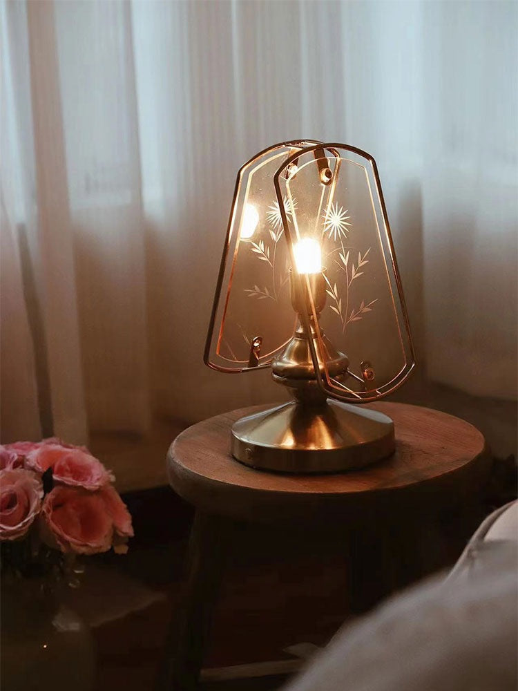 Illuminated table lamp showing warm glow and floral etching