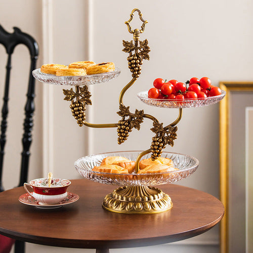 3-tier brass and glass serving stand with fruit and desserts on round dining table