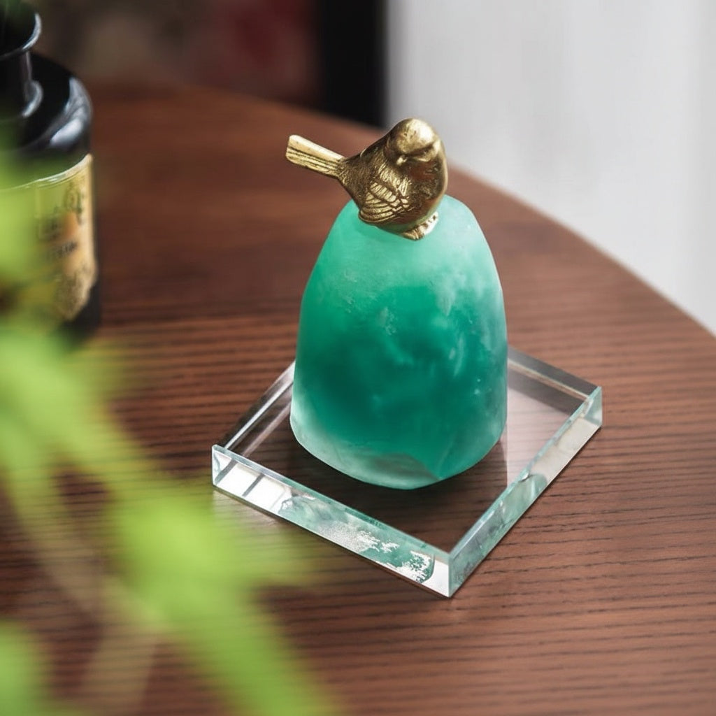 Brass and green stone bird figurine styled on a wooden table