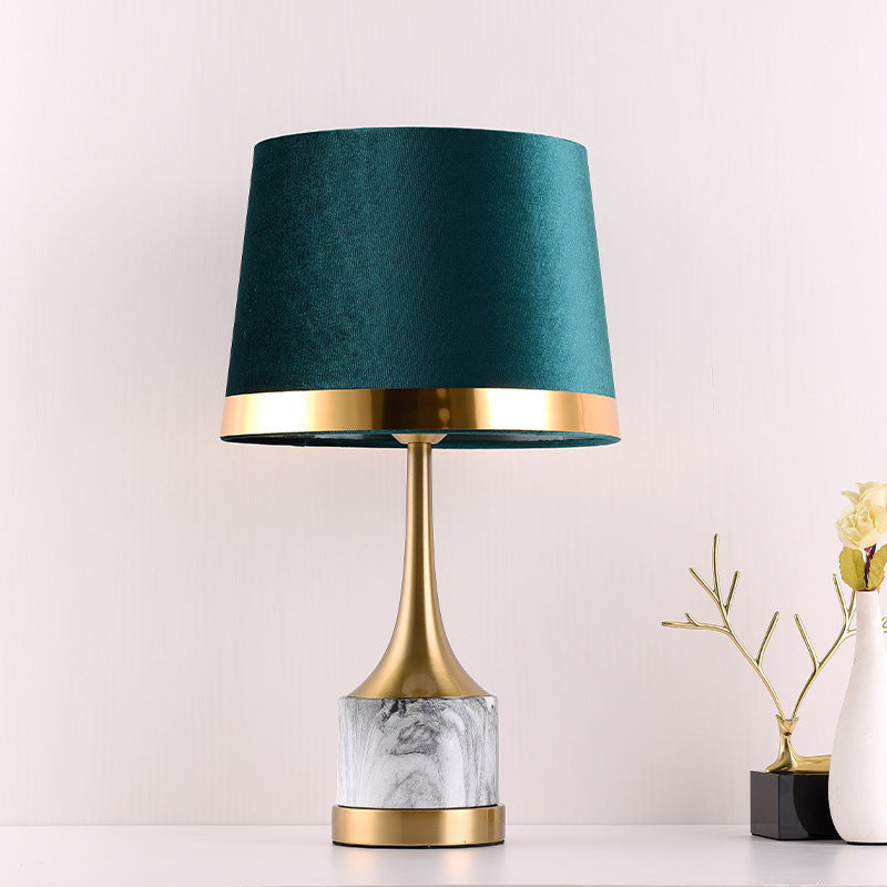 Front view of gold metal and marble lamp with emerald shade on white background