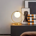 Brass ring table lamp with illuminated globe on console