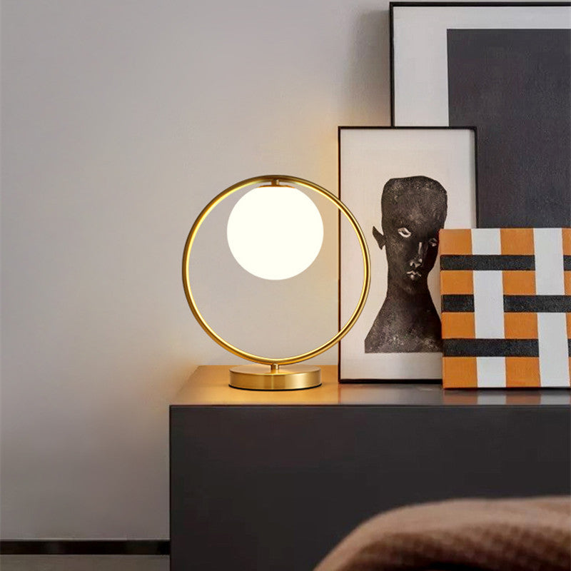 Brass ring table lamp with illuminated globe on console