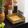 Brass square lattice napkin holder on table with fruit and jars