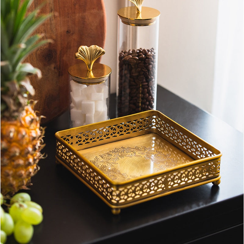 Brass square lattice napkin holder on table with fruit and jars