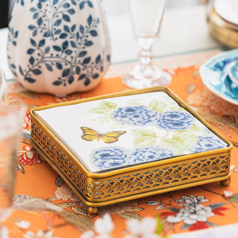Brass napkin holder filled with floral paper napkins on dining table