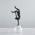 Front view of bronze finish acrobat sculpture on white marble base