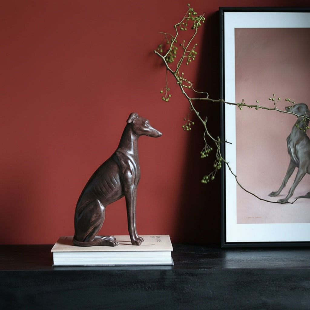 Side profile of bronze finish seated greyhound sculpture on books
