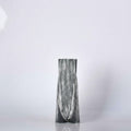 Front view of brushed black and white ceramic faceted vase against white background