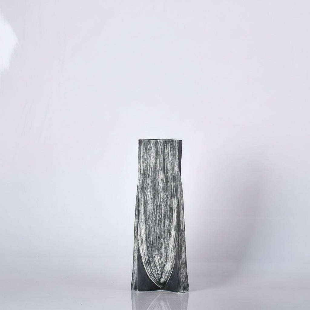 Front view of brushed black and white ceramic faceted vase against white background