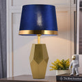 Front view of brass and blue velvet lamp lit up