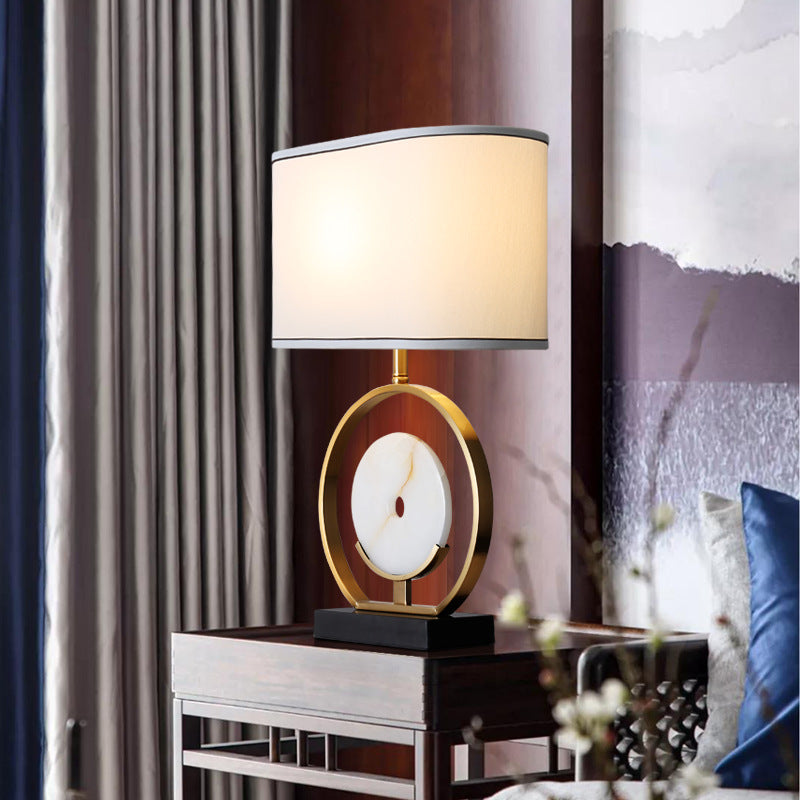Front view of brushed brass and marble ring table lamp lit up