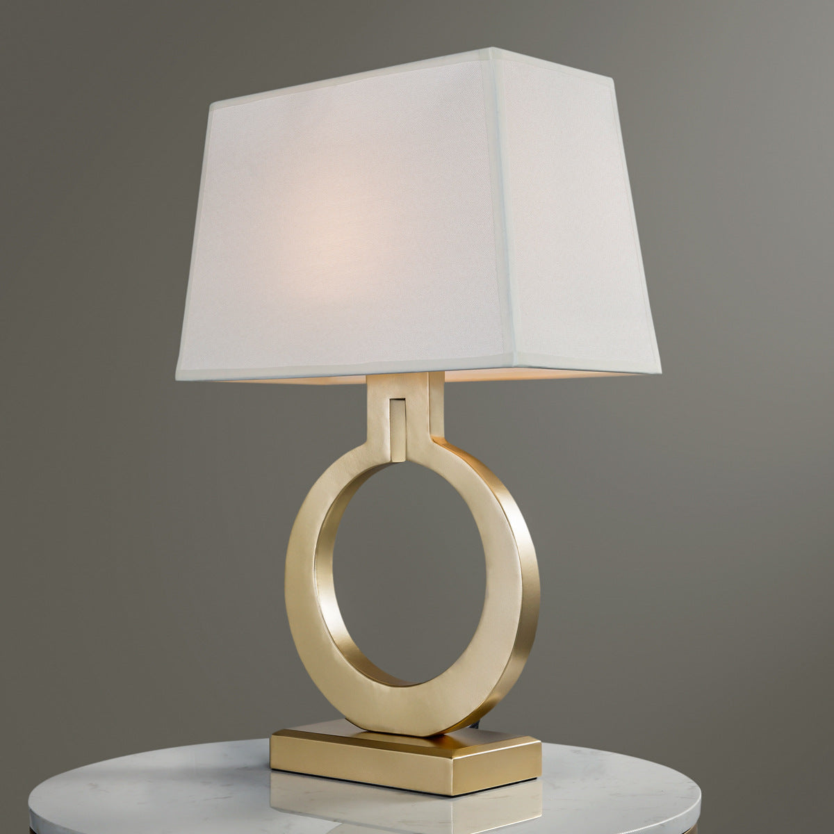 Front view of brushed brass open ring table lamp with white shade
