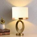 Front view of brushed gold oval table lamp with white shade