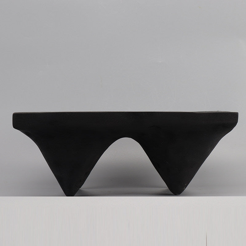 Side profile of black carbonized wood pedestal tray showing leg detail