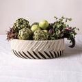 Side view of carved wood bowl filled with artichokes