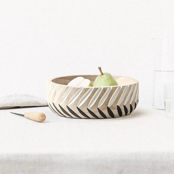Close up of carved details on wooden bowl with pear