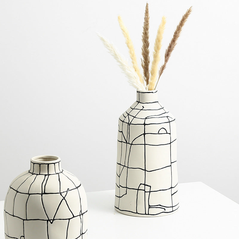 Tall cream ceramic vase with black lines holding dried pampas grass