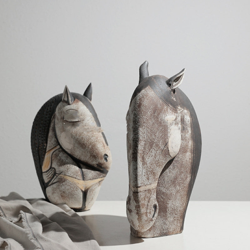 Two distressed ceramic abstract horse head sculptures displayed together