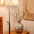 Ceramic bird and branch globular vase on wooden table with lamp